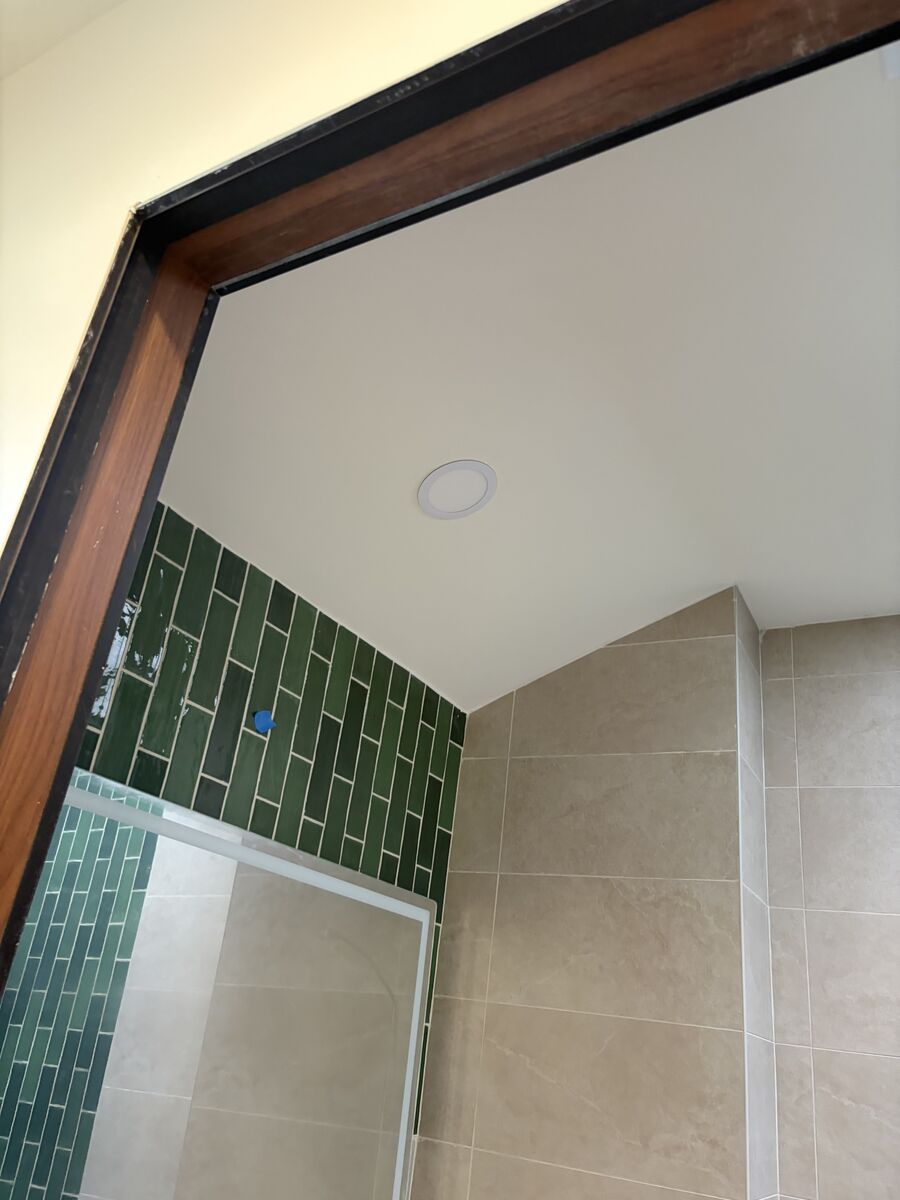 Finished ceiling corner in bathroom with green tile